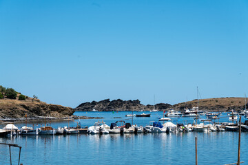 Cove and fishing village of Port Lligat in front of Salvador Dal&iacute; House-Museum, Cadaques city, Spain. Small boats and sailboats parked in a cozy rocky harbour at blue sea.