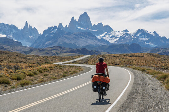 Cyclist riding winding road toward El Chalten with Fitz Roy massif, Argentina