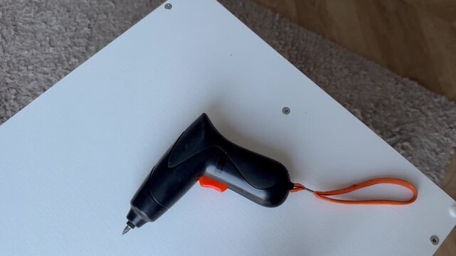 Cordless electric screwdriver on white furniture - with the tip facing to the left
