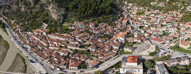 Aerial view of Berat&rsquo;s hillside homes and riverfront streets, showcasing the iconic white fa&ccedil;ades and dense traditional rooftops.