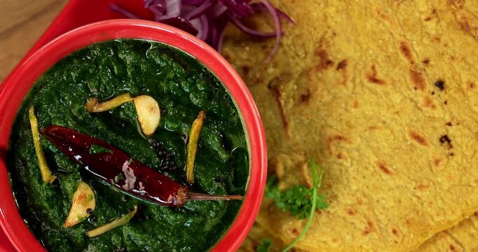 Makki Ki Roti & Sarson Ka Sag is basically Corn floor flat bread & curry using mustard greens respectively. Popular Punjabi food. Served in a bowl and plate over moody background. selective focus