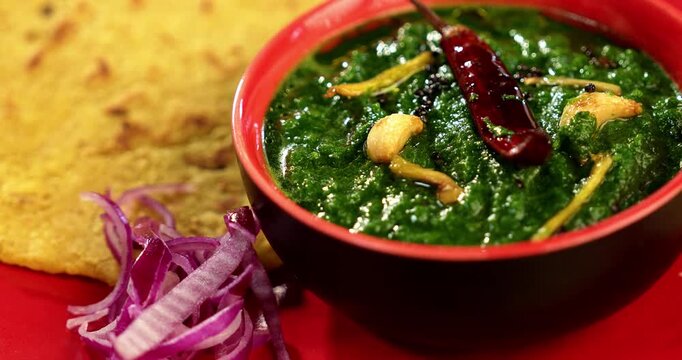 Makki Ki Roti & Sarson Ka Sag is basically Corn floor flat bread & curry using mustard greens respectively. Popular Punjabi food. Served in a bowl and plate over moody background. selective focus