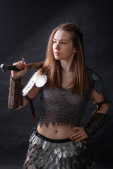Obraz premium Portrait of a young woman, fantasy warrior in armor with a sword in her hands isolated on a dark background.