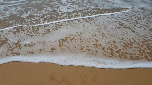 2025 written on the sand washed away by the wave at sunset