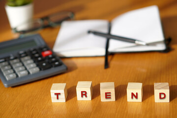 TREND. Financial and business concepts. Letters on wooden blocks with a calculator and notebook