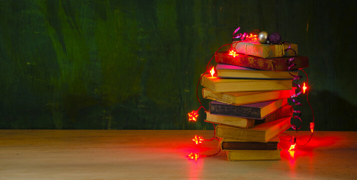 Fototapeta giving books for christmas,christmas  gift,present,reading,literature,education, christmas,holiday concept with heap of books, christmas lights and decoration