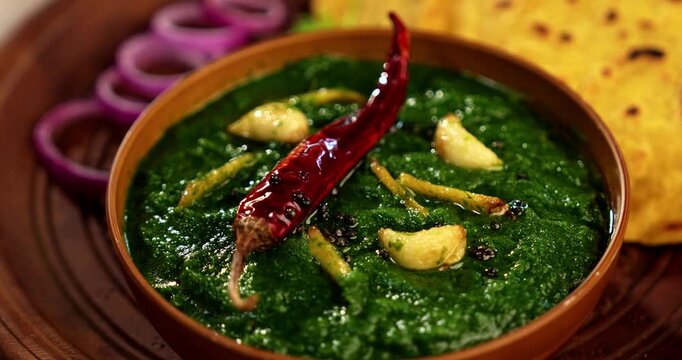 Makki Ki Roti & Sarson Ka Sag is basically Corn floor flat bread & curry using mustard greens respectively. Popular Punjabi food. Served in a bowl and plate over moody background. selective focus