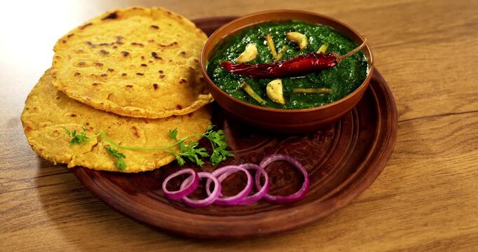 Makki Ki Roti & Sarson Ka Sag is basically Corn floor flat bread & curry using mustard greens respectively. Popular Punjabi food. Served in a bowl and plate over moody background. selective focus