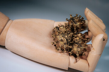 Close-up of a hand holding several small bronze sculptures in the shape of stylized viruses with...