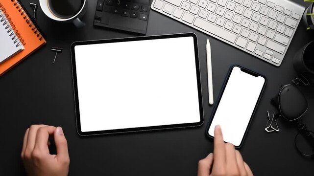 Person using tablet and phone on desk.