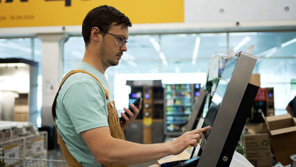 Man shopper enters his phone number to get a discount at a self-checkout in a hardware store