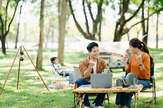 Asian couple enjoys a peaceful camping morning with coffee, breakfast, music, and devices in nature