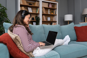 Remote work at home young woman stream music through headphones concentrates on laptop handling online tasks and messages as independent freelancer who values productivity comfort focus and privacy