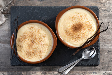 Creamy homemade Spanish custard served in a bowl on wooden table. Top view