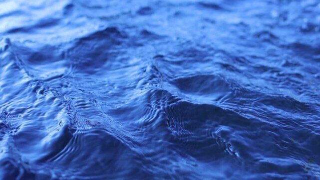 Natural background of blue water surface of sea or ocean with waves and light reflections. View of motion water swimming pool with ripples and sun glare. Unstable social issues
