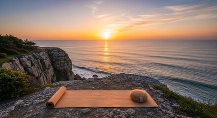Yoga mat and meditation cushion on cliff with ocean view at sunrise for wellness and relaxation