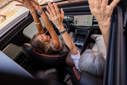 Senior couple enjoying car road trip with open sunroof