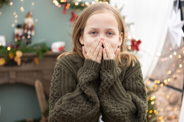 Young girl surprises her friends while celebrating winter festivities at a decorated indoor venue filled with lights and decorations
