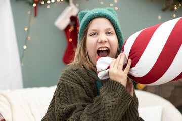 Child enjoying a festive moment with a striped pillow during a cozy winter celebration at home