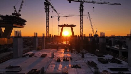 Construction site with large cranes and building structures at sunset - Powered by Adobe