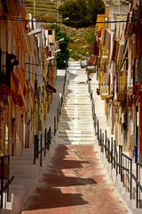 uliczka w południowej europie, pomarańczowe domy i białe schody pod górę w hiszpańskim miasteczku, Spanish town with houses and street stairs, ocher-painted houses 