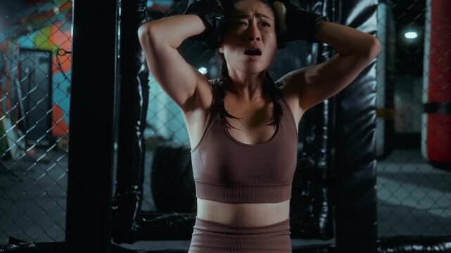 Exhausted and emotional, the Japanese MMA fighter kneels in the cage, crying in frustration and disappointment after the fight, sweaty and overwhelmed by defeat.