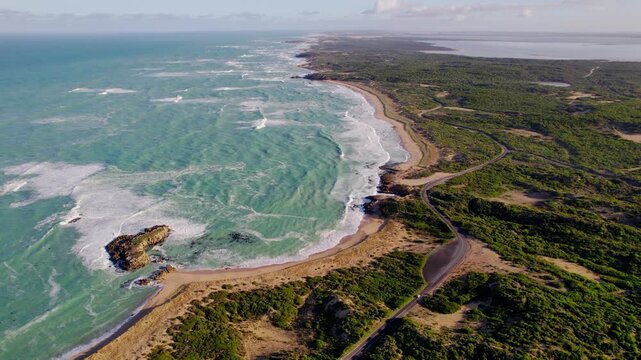Aerial coastal view of the coast of Beachport, South Australia, showing the road running along the shoreline. Clear water, rocky edges and bright coastal scenery create a vivid landscape.