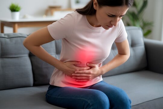 A Woman Experiencing Abdominal Pain, Shown Gripping Her Stomach and Frowning, Displaying Symptoms of Discomfort.
