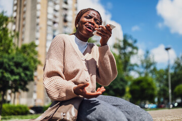African American woman is distraught and anxious while using smartphone for online messaging and voice call.