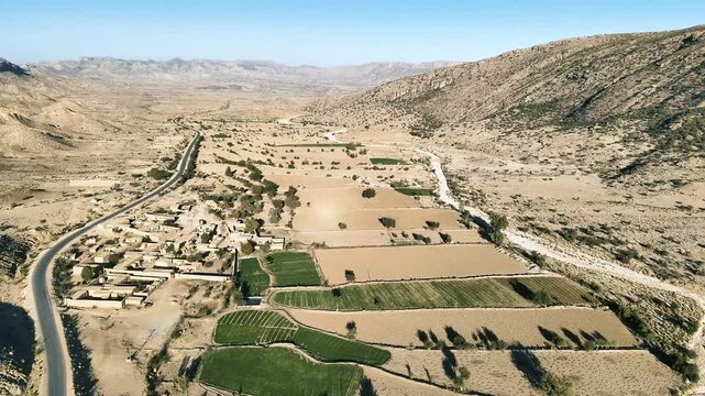 4k drone aerial view - arid dry mountain valley besides long empty asphalt road Balochistan, Pakistan