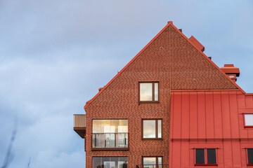 Modern brick residential buildings with red roofs in urban neighborhood at dusk.