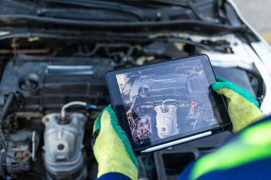 Close-up of display of African mechanic smart tablet inspecting a car engine, troubleshooting and performing routine maintenance with digital assistance