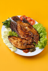Food photography showcasing Indonesian-style grilled gourami fish served with sambal and vegetables