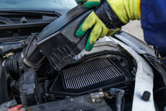 Close-up, hands of African mechanic carefully inspecting air filter housing of a car, routine maintenance