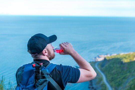 Man drinking water during a hike with ocean view