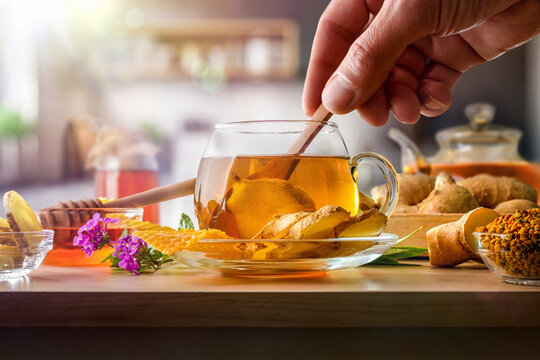 Stirring cup with ginger infusion with honey in the kitchen