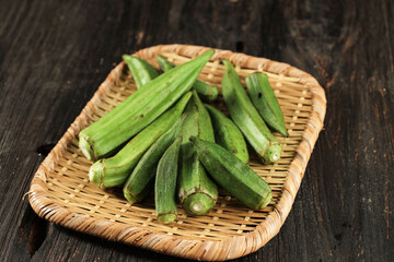 Okra in Bamboo Sieve above Wooden Table