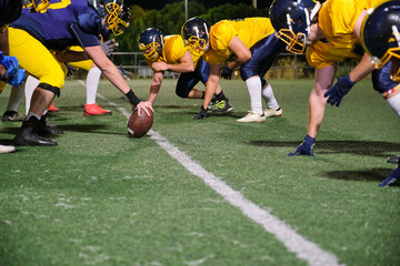 American football players positioning for battle on the line of scrimmage at night