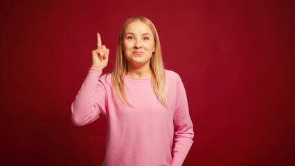 Fototapeta premium Pensive worry blonde woman thinking and worry looking away isolated on red background