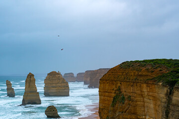 The Twelve Apostles, The Port Campbell Limestone in rainy day with helicopter flying at Port Campbell, Victoria Australia.