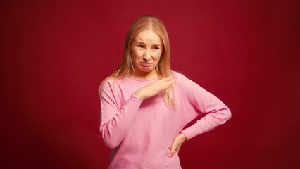 Serious pensive blonde woman to smell unpleasant odor o cover one's nose isolated on red background