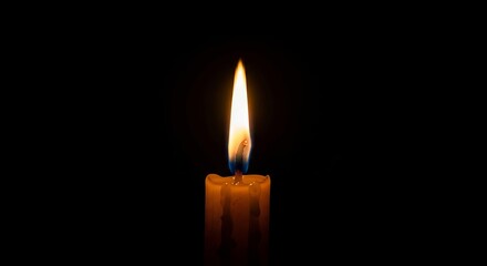 Burning candle flame in darkness, warm glow