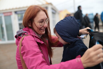 Mother smiling fixing child's hood outdoors