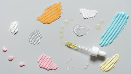 Samples of cosmetic products on gray background, cream, gel, serum, oil, top view, flat lay