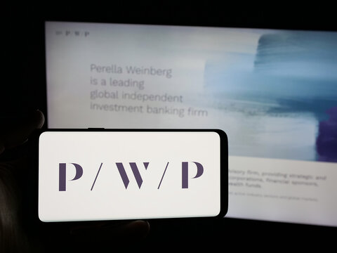Stuttgart, Germany - 11-19-2025: Person holding smartphone with logo of US company Perella Weinberg Partners (PWP) on screen in front of website. Focus on phone display.