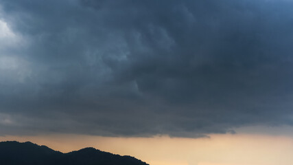 Dark storm clouds forming over the mountains at sunset. Rainy season sky. Weather forecast...