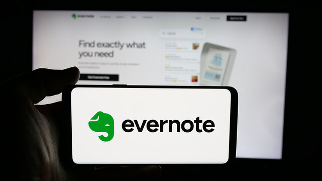 Stuttgart, Germany - 11-19-2025: Person holding cellphone with logo of note-taking software company Evernote on screen in front of webpage. Focus on phone display.