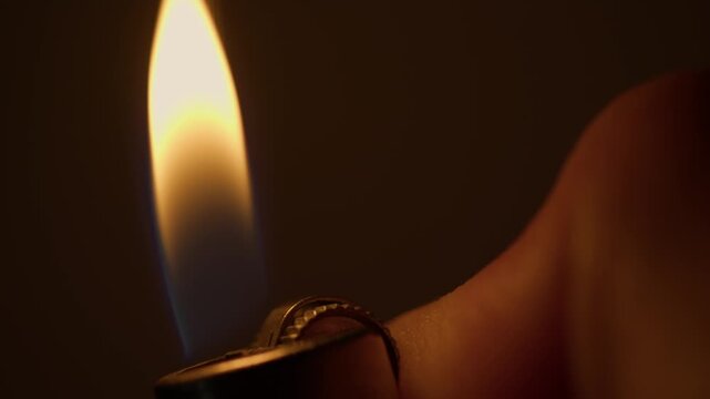 Close-up shot of a hand repeatedly flicking a lighter on and off.