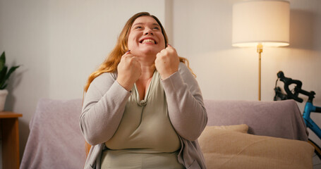 Obraz premium Overweight woman shakes hands and shouts expressing sudden joy