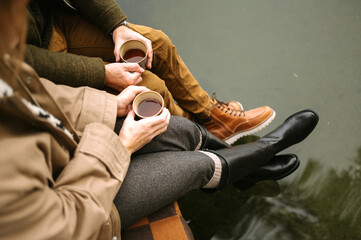 Couple enjoying coffee by the water in autumn attire